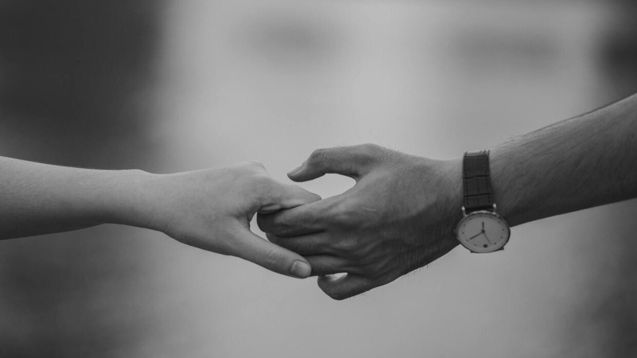 monochrome photo of couple holding hands